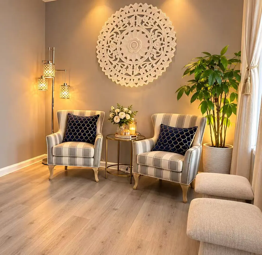 Front lounge with striped armchairs, upholstered ottomans and a tall potted plant by the window